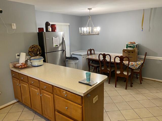 kitchen featuring stainless steel refrigerator, light tile patterned flooring, a chandelier, and hanging light fixtures