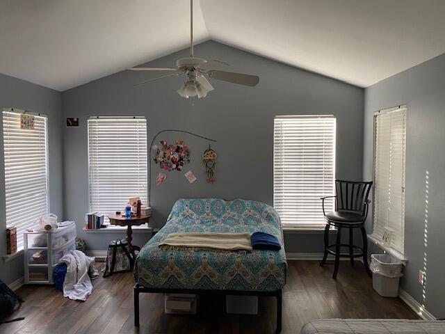 bedroom with dark wood-type flooring, vaulted ceiling, and ceiling fan