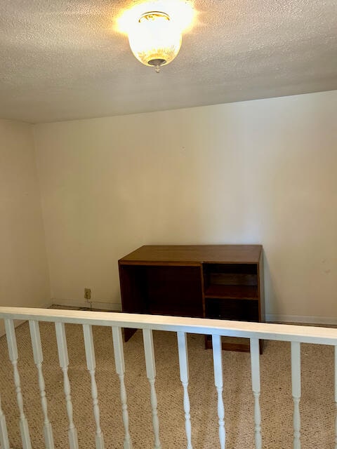 stairs with carpet and a textured ceiling