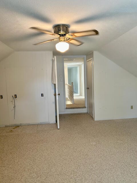 additional living space with vaulted ceiling, a textured ceiling, and ceiling fan