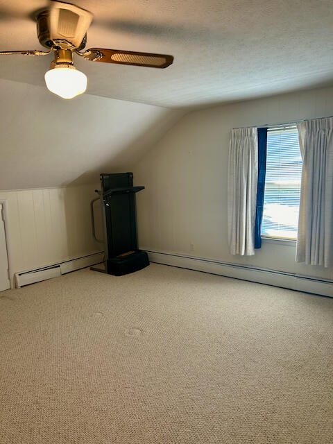 bonus room featuring a textured ceiling, ceiling fan, vaulted ceiling, baseboard heating, and carpet