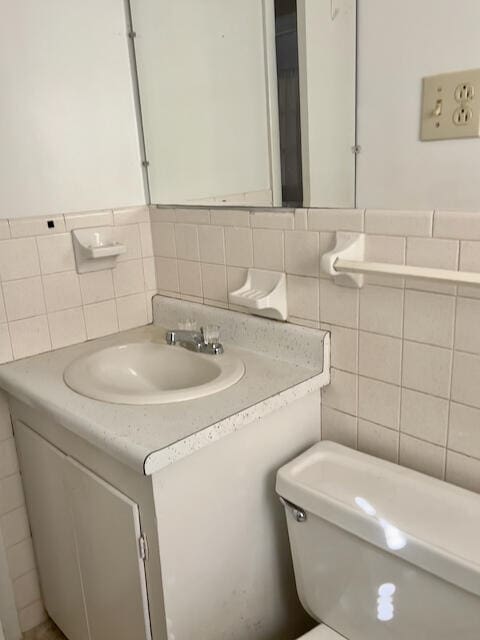 bathroom featuring tile walls, vanity, backsplash, and toilet