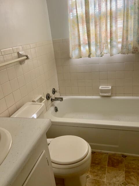 bathroom featuring a bathtub, tile walls, toilet, vanity, and tile patterned flooring