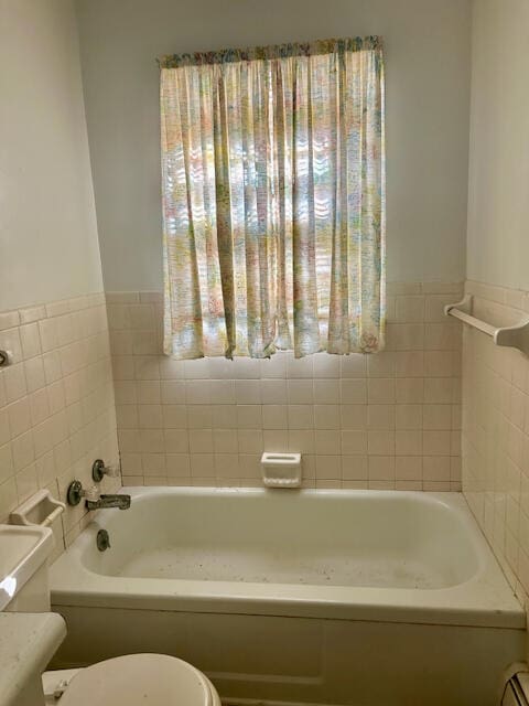 bathroom featuring a tub to relax in, tile walls, and toilet