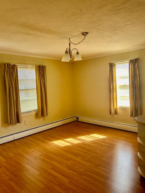 empty room with ornamental molding, hardwood / wood-style floors, a textured ceiling, and an inviting chandelier