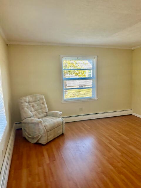 living area with wood-type flooring, a baseboard radiator, and ornamental molding