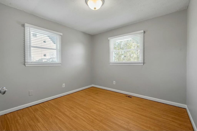 empty room with visible vents, baseboards, and wood finished floors