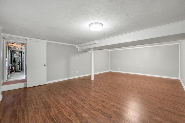 finished below grade area with a textured ceiling, dark wood finished floors, and baseboards