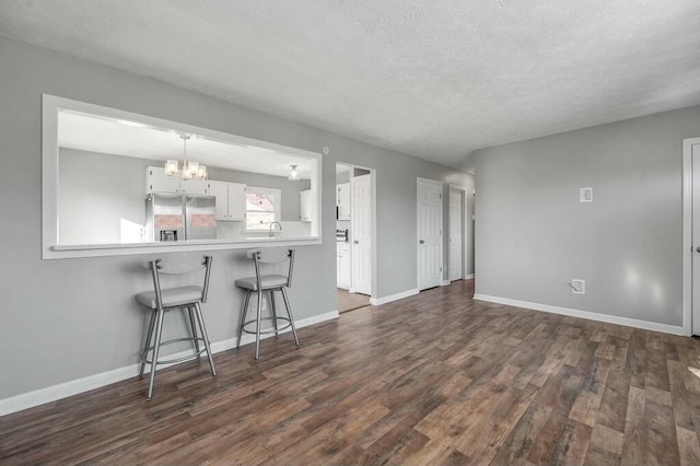 kitchen with a peninsula, white cabinetry, light countertops, stainless steel fridge with ice dispenser, and dark wood finished floors