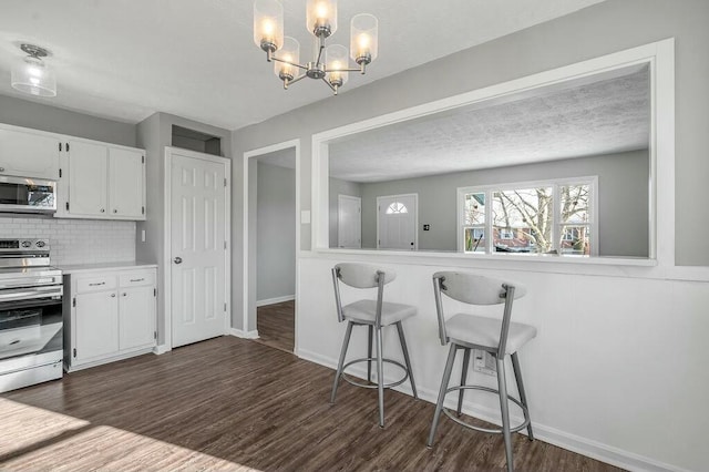 kitchen with stainless steel appliances, light countertops, white cabinets, and dark wood-style floors