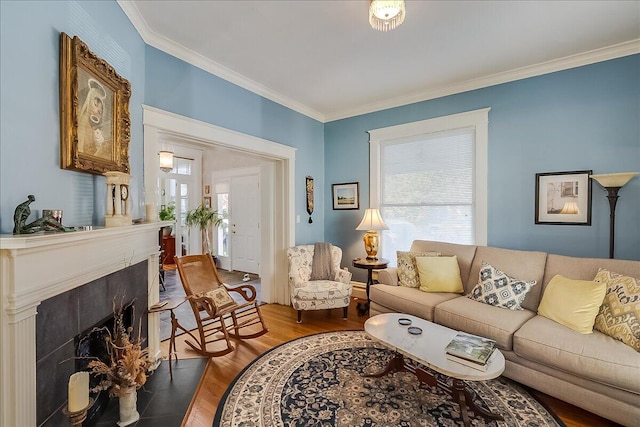 living room with ornamental molding, a tiled fireplace, and hardwood / wood-style flooring