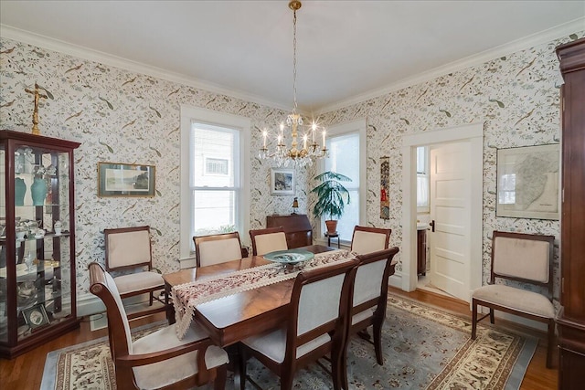 dining space with dark wood-type flooring, a notable chandelier, and ornamental molding