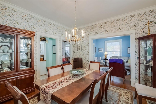 dining room with crown molding, hardwood / wood-style flooring, and an inviting chandelier