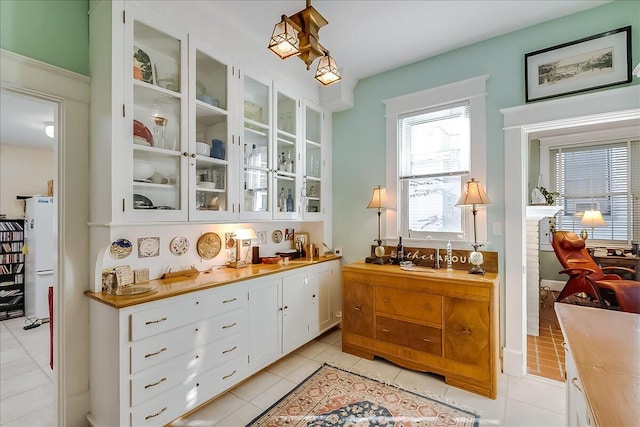 bar featuring white cabinetry, light tile patterned flooring, and white refrigerator