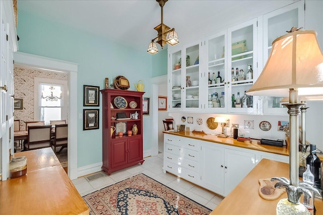 interior space featuring white cabinetry, wood counters, light tile patterned flooring, and hanging light fixtures