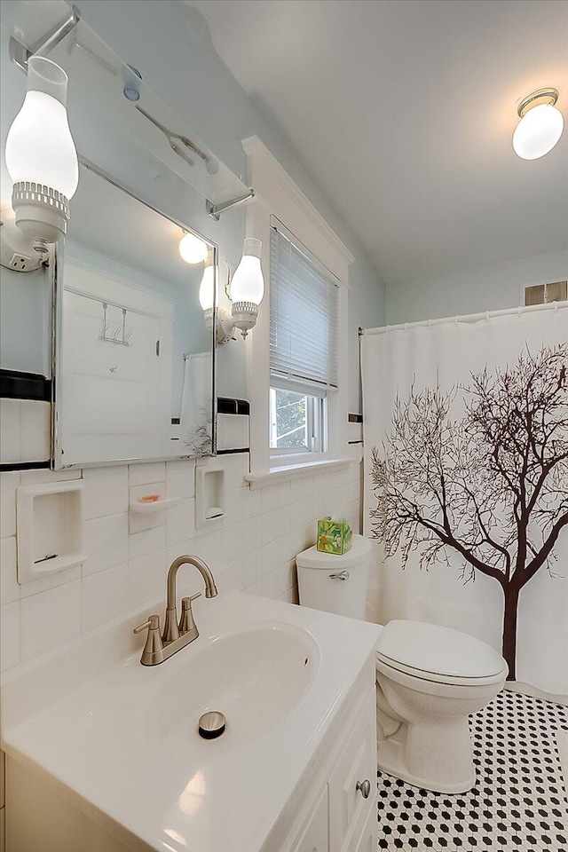 bathroom featuring tile patterned floors, toilet, vanity, curtained shower, and tile walls