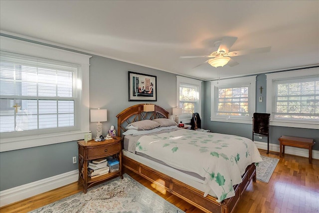 bedroom featuring hardwood / wood-style floors, multiple windows, and ceiling fan