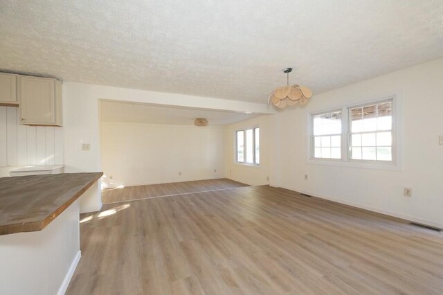 unfurnished living room featuring light wood-type flooring and a textured ceiling