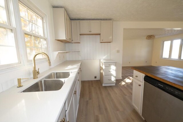 kitchen featuring white cabinetry, sink, a textured ceiling, stainless steel dishwasher, and light wood-type flooring