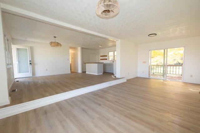 unfurnished living room featuring light wood-type flooring and a textured ceiling