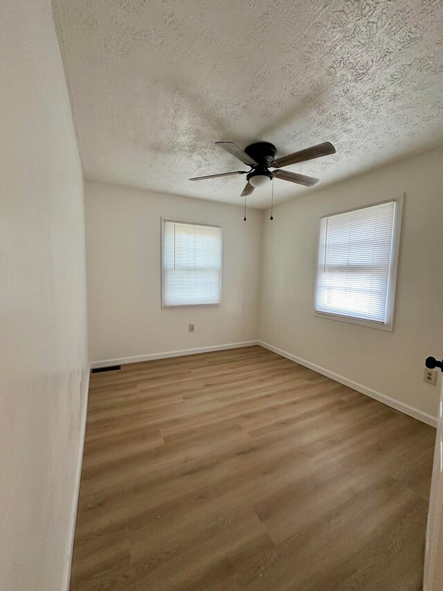 unfurnished room featuring hardwood / wood-style floors, ceiling fan, and a textured ceiling