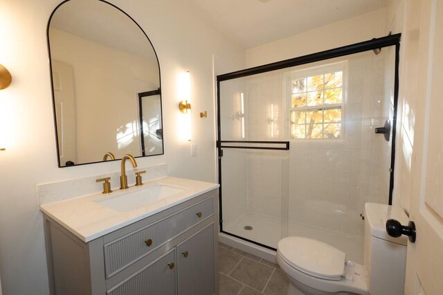 bathroom with tile patterned flooring, vanity, toilet, and a shower with door