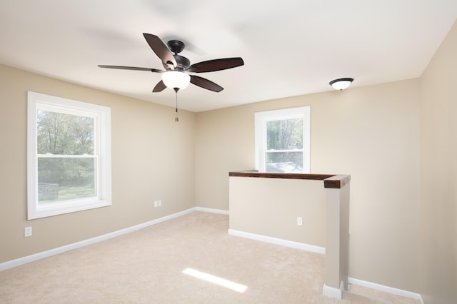 carpeted spare room with ceiling fan and plenty of natural light