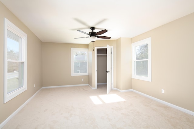 unfurnished bedroom featuring ceiling fan, light carpet, and multiple windows