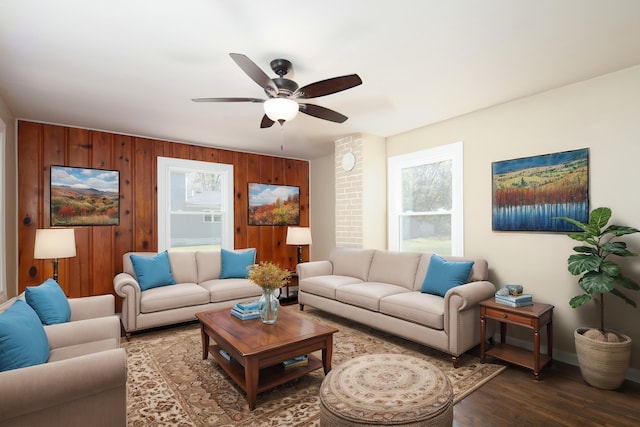 living room featuring ceiling fan, hardwood / wood-style flooring, and wood walls