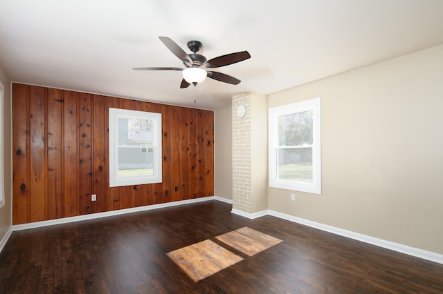 unfurnished room featuring ceiling fan, dark hardwood / wood-style floors, and wood walls