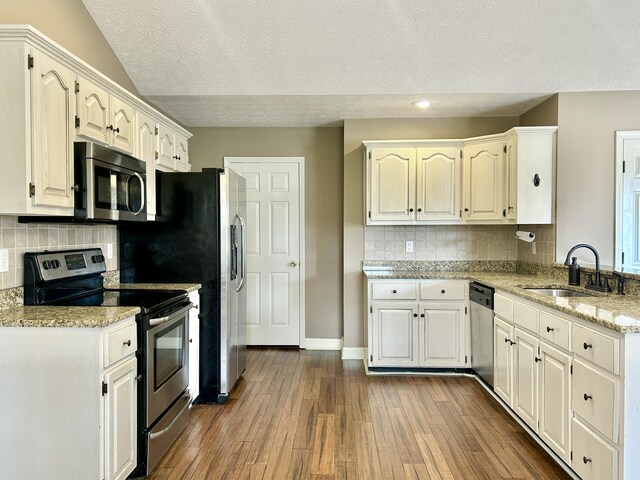 kitchen with stainless steel appliances, white cabinetry, dark wood-type flooring, and dark stone countertops