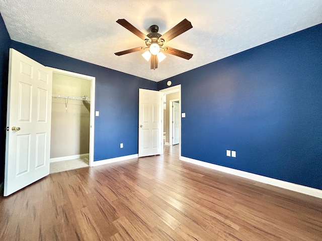 unfurnished bedroom with wood-type flooring, ceiling fan, a textured ceiling, and a closet