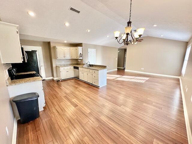 kitchen with lofted ceiling, light hardwood / wood-style flooring, kitchen peninsula, pendant lighting, and stainless steel appliances