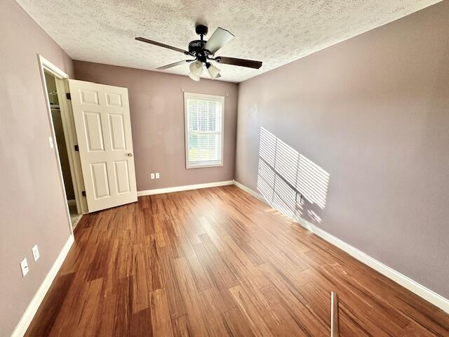 unfurnished bedroom featuring ceiling fan, wood-type flooring, and a textured ceiling