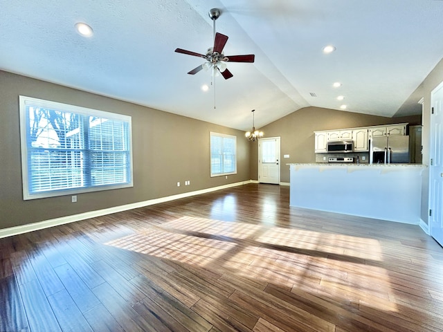 unfurnished living room featuring lofted ceiling, dark hardwood / wood-style floors, and ceiling fan with notable chandelier