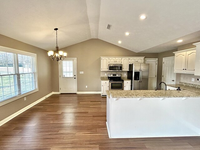 kitchen with appliances with stainless steel finishes, sink, light stone counters, and dark hardwood / wood-style flooring