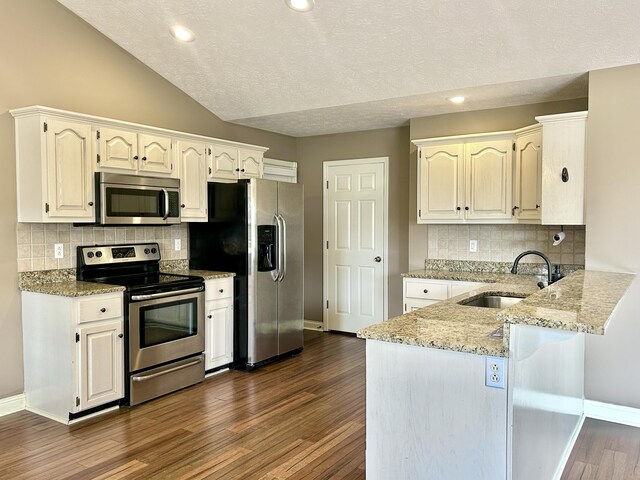 kitchen with hardwood / wood-style floors, decorative light fixtures, white cabinets, stainless steel dishwasher, and kitchen peninsula