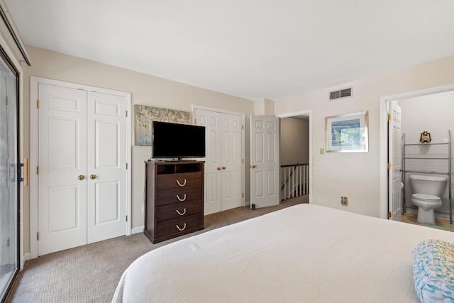 carpeted bedroom featuring two closets and ensuite bath