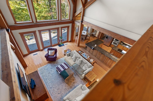 living area featuring light wood-type flooring, visible vents, and a high ceiling