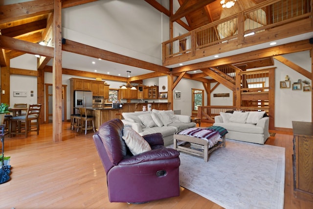 living room featuring light wood-style floors, stairs, high vaulted ceiling, and beamed ceiling