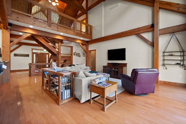 living room featuring high vaulted ceiling, wood finished floors, visible vents, baseboards, and beam ceiling