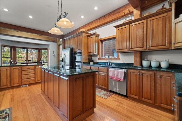 kitchen featuring brown cabinets, a center island, stainless steel appliances, pendant lighting, and a sink