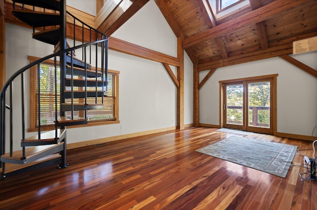 unfurnished living room featuring a skylight, wood finished floors, beamed ceiling, baseboards, and stairs