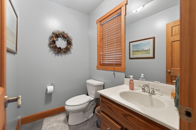 bathroom with baseboards, vanity, and toilet