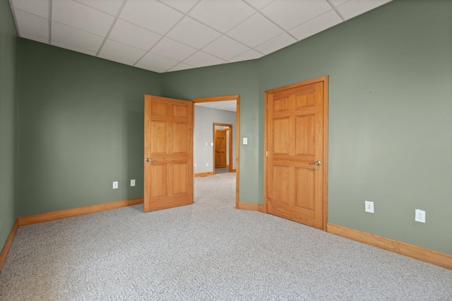 empty room with carpet, baseboards, and a drop ceiling