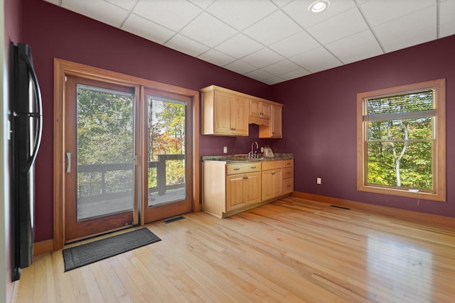 interior space featuring light brown cabinets, a sink, visible vents, freestanding refrigerator, and light wood finished floors