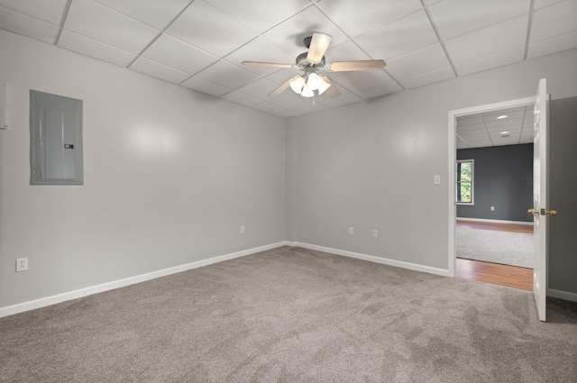 unfurnished room featuring carpet, a paneled ceiling, ceiling fan, electric panel, and baseboards