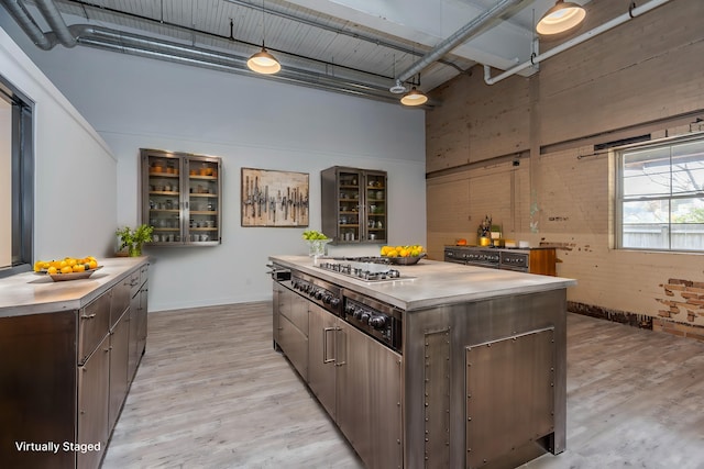 kitchen with a high ceiling, light wood-type flooring, dark brown cabinetry, and a center island