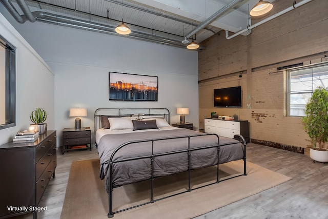 bedroom with a high ceiling and wood-type flooring