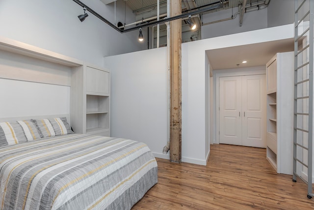 bedroom with light hardwood / wood-style flooring and a towering ceiling